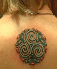 Tatuaje de la imagen de un triskel adornado con tres triquetas, realizado en la parte inferior de del cuello de una persona de piel blanca.