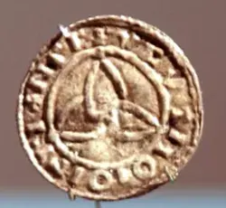 Foto de antigua moneda metálica en cuyo centro está tallado el símbolo de la triqueta celta